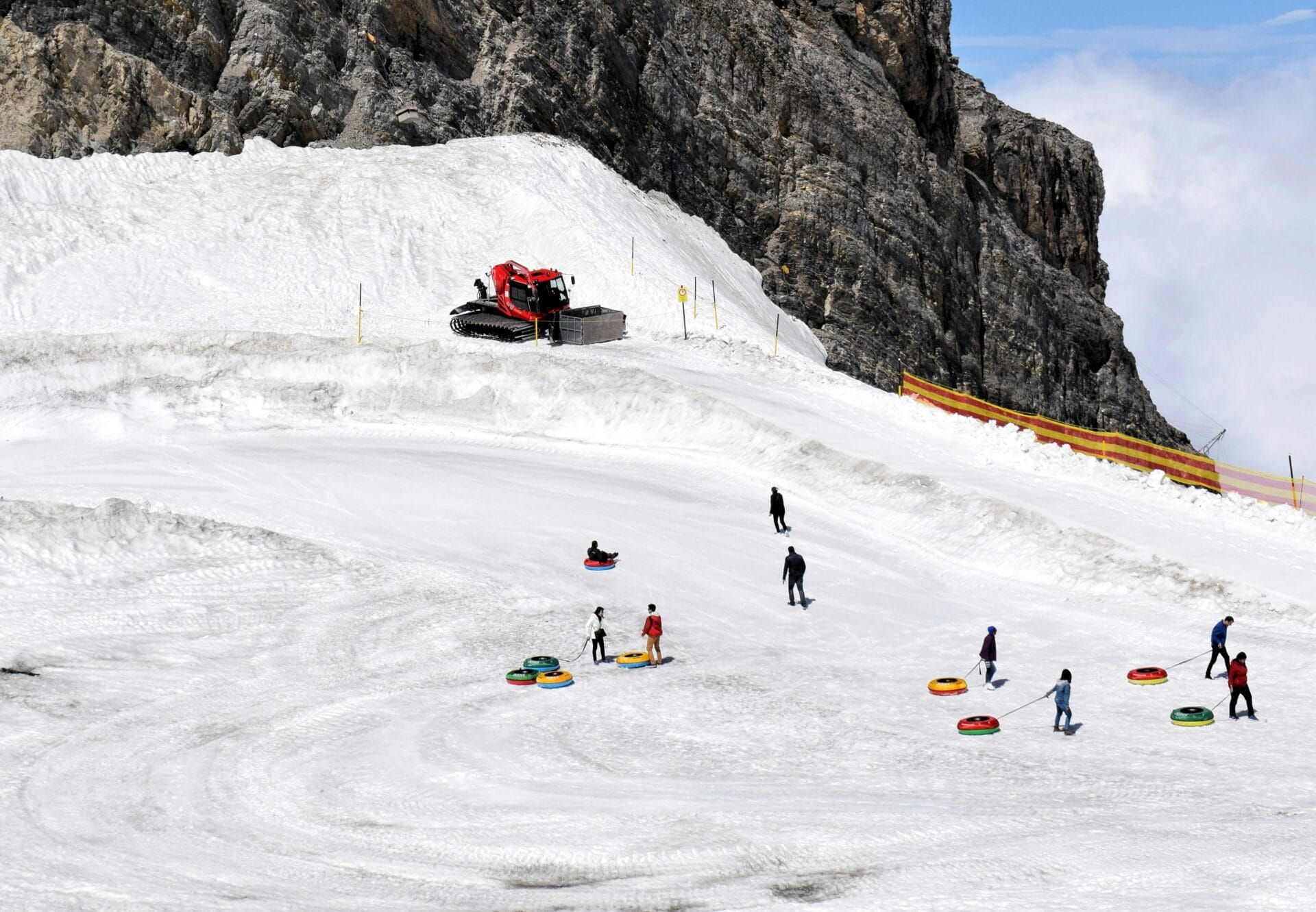 People enjoying snow tubing on a sunny winter day at a mountain resort.