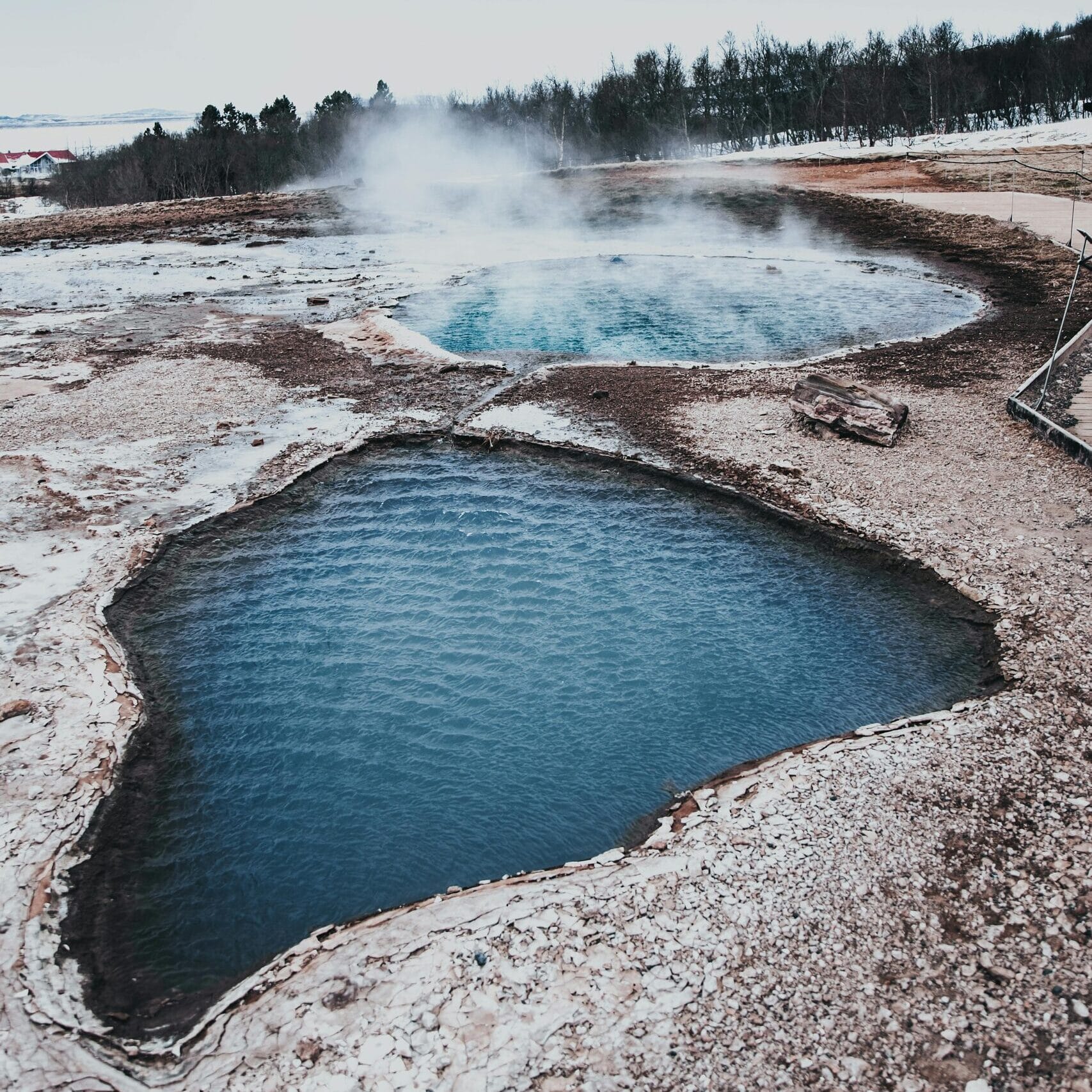 From above of Blesi pool and Fata erupting geyser located at Geysir Hot Springs in Iceland against cloudy sky
