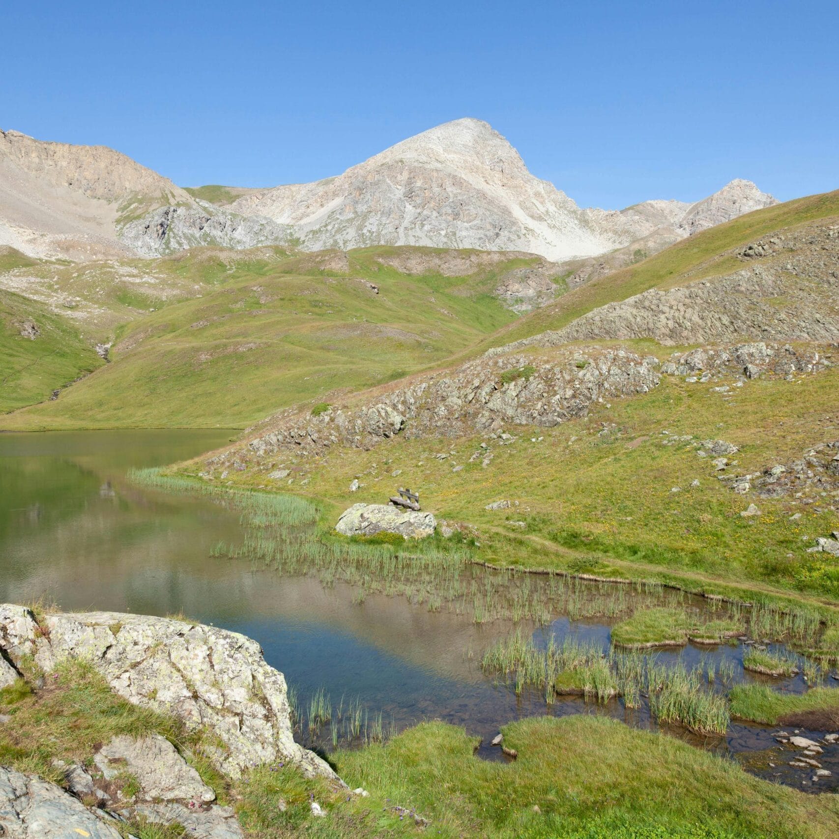 Tranquil mountain landscape with clear skies and a serene stream in Cervières, France.