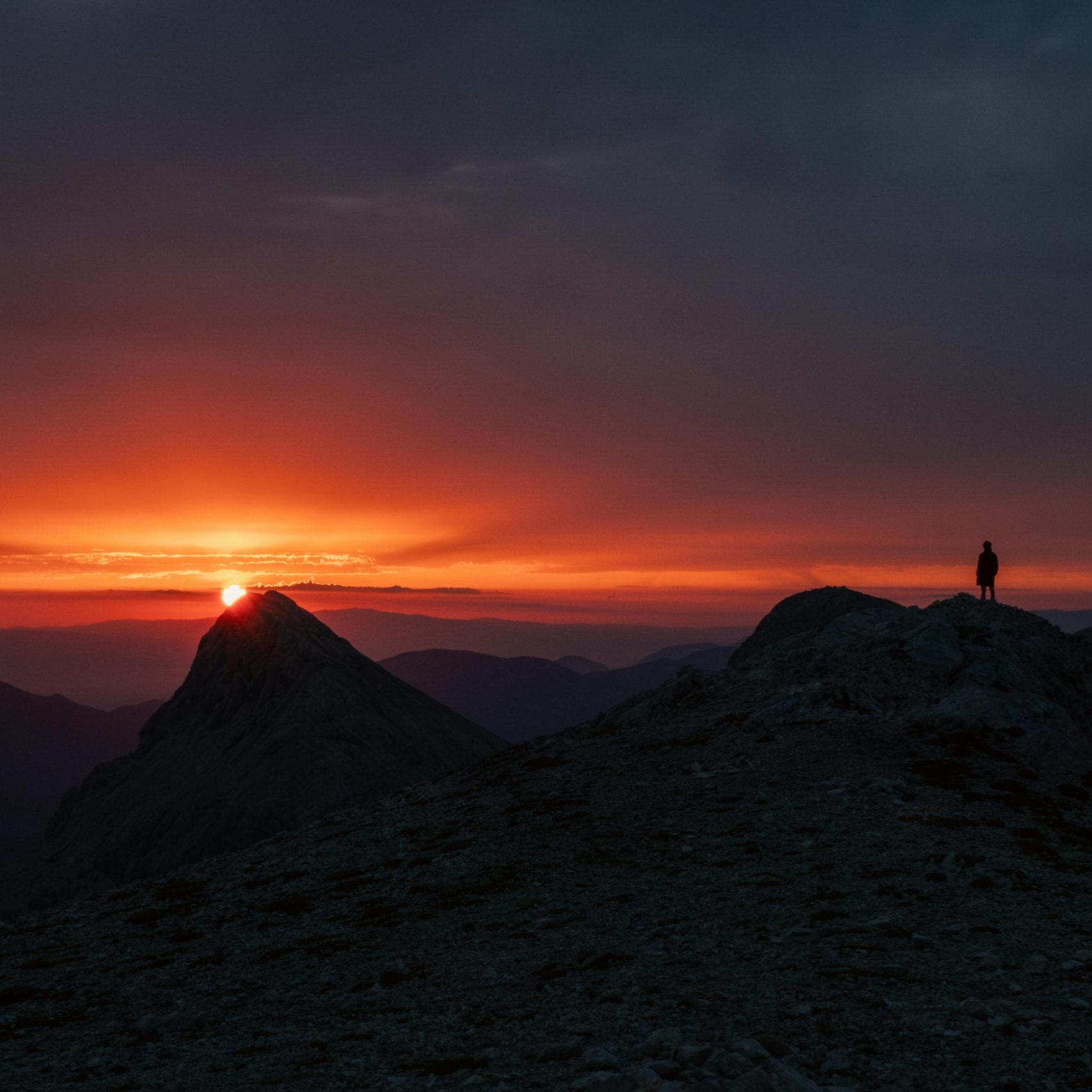Majestic sunset view over mountains in Slovenia with a lone silhouette on the ridge.
