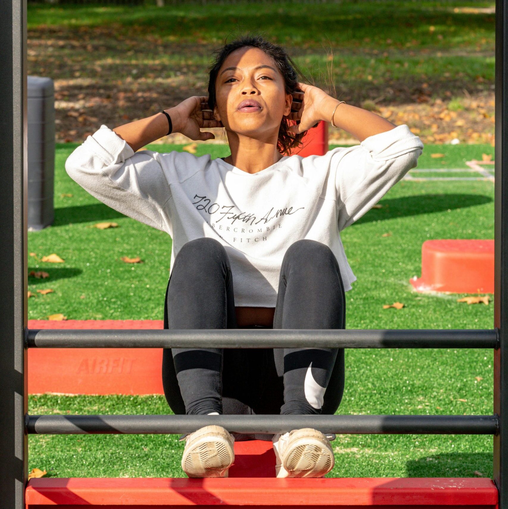A woman exercises outdoors performing sit-ups on fitness equipment in Villetaneuse, France.