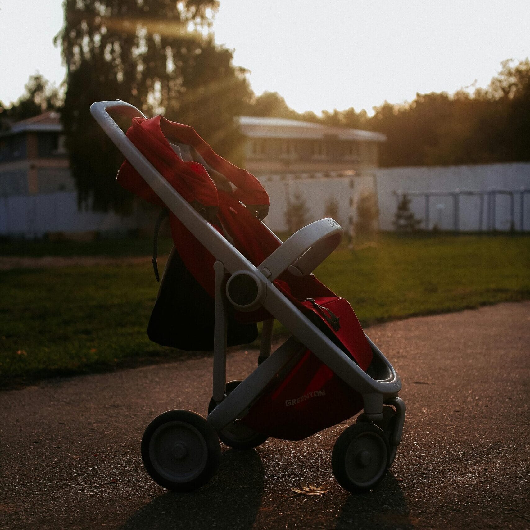 A baby stroller on a path during sunset, casting a shadow on the ground.