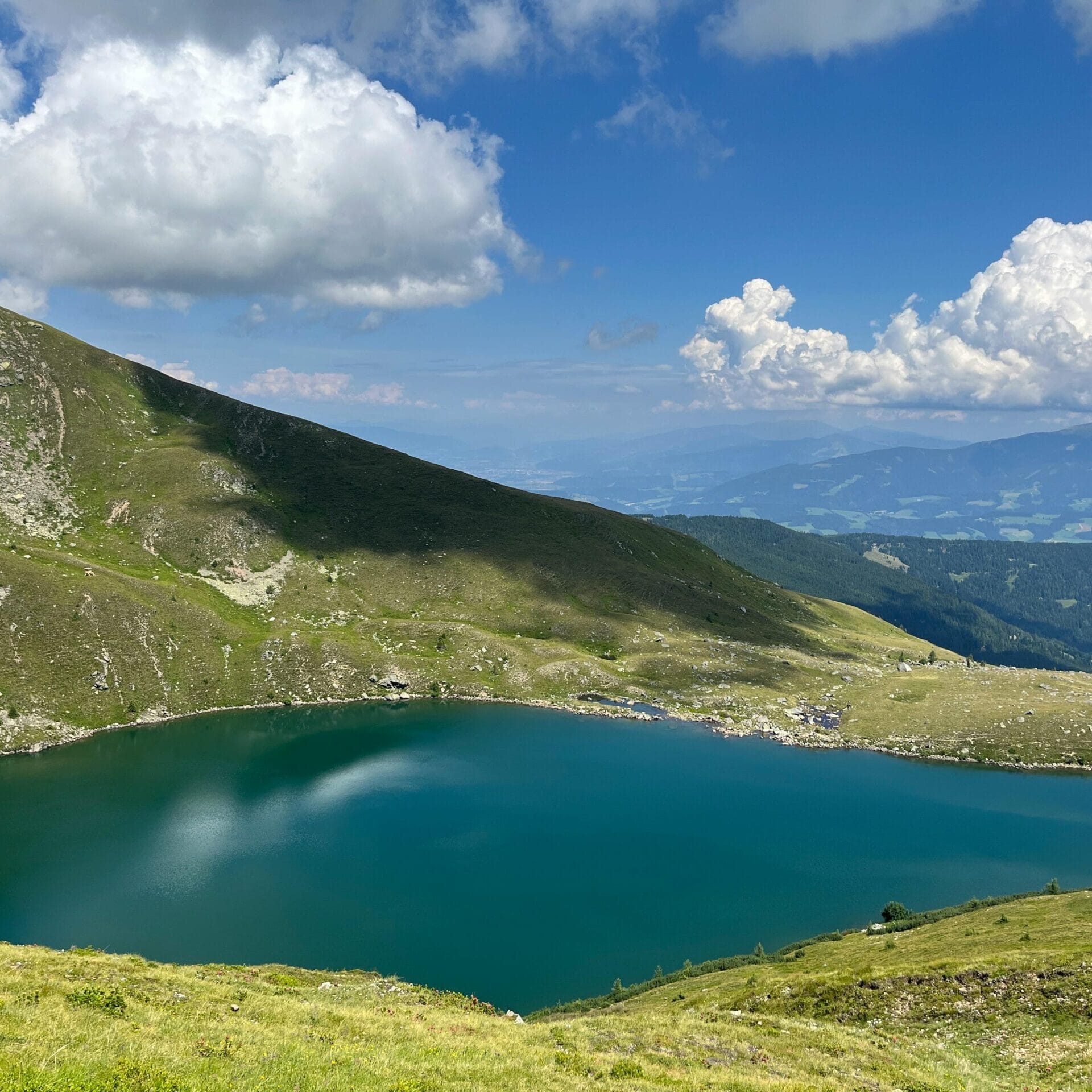 A breathtaking view of an alpine lake surrounded by lush mountains in Styria, Austria.