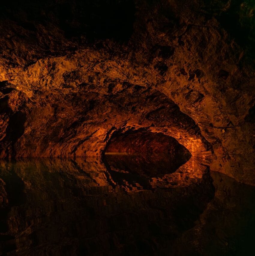 Explore a dimly lit cave in Austria with stunning water reflections.