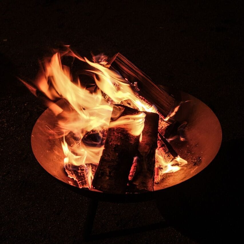 A close-up view of a campfire, showcasing vibrant flames against a dark night backdrop.